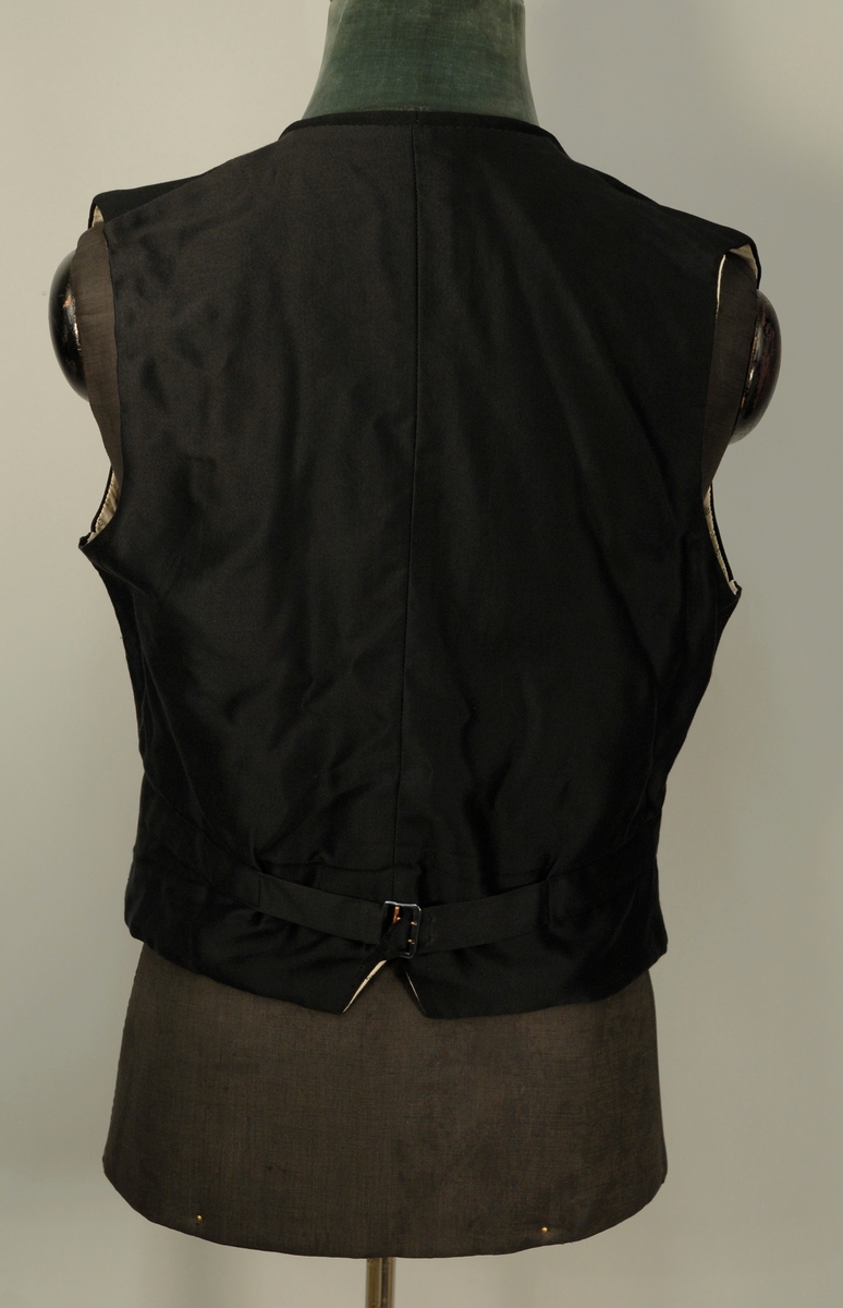 A: Jakke
Dyp V-formet halsskjæring, enkeltspent med ein knapp og knapphull. Spisse slag, kledd med diagonalvevd svart natursilke. Brystlomme og stikklomme i hoftehøgde i kvar side. Tosømserme med tre knapper. For av satengsvevd mercerisert bomull.

B: Bukse
Stikklomme øvert i kvar sidesøm og øverst i kvar sidesøm og øverts på høgre bakstykke. Gylf med skjult lukkning med tre knapper og knapphull. Splitt midt bak, liten trekantet innskjøtning, spensel med spenne. Linning 2 cm høg bak, 3,5 cm foran og lukkes med hekte. Seks blålige metallknapper for bukseseler i linningen som er foret med med kvitt satengvevd bomullstøy med trykte småfigurer.

C: Vest
Dyp. U-formet halsskjæring, enkeltspent med fire knapper og knappehull. Forstykkene avsluttes i spisser. Skråstilt stikklomme på v. forstykke, tilsvarende i livhøgde på kvart forstykke. Rygg av samme tøy som for i jakke. Splitt midt bak og i sidene. Spensel med spenne. Fór av samme tøy som bukse.