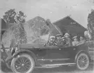 Ett sällskap i bil, en Buick 1923 6 cylindrig, framför en stor sten.
