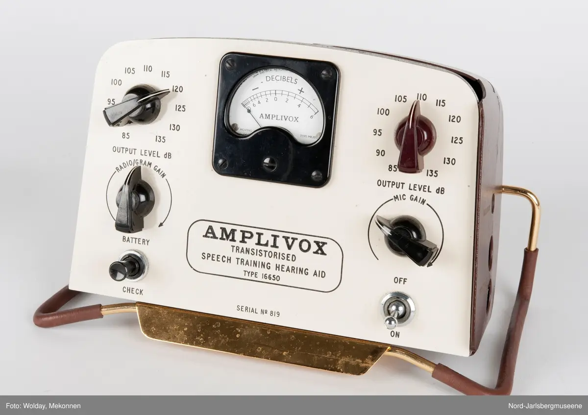 Rektangulært apparat med støtteben i gummipolstret messing (regulerbare). Fronten har målenål, reguløeringsbrytere, av-og-på knapp mm, i bakelitt. Tre uttak for audio på sidn. Bakdekslet i plast er delvis knust, slik at transitorutstyret innvendig er synlig.