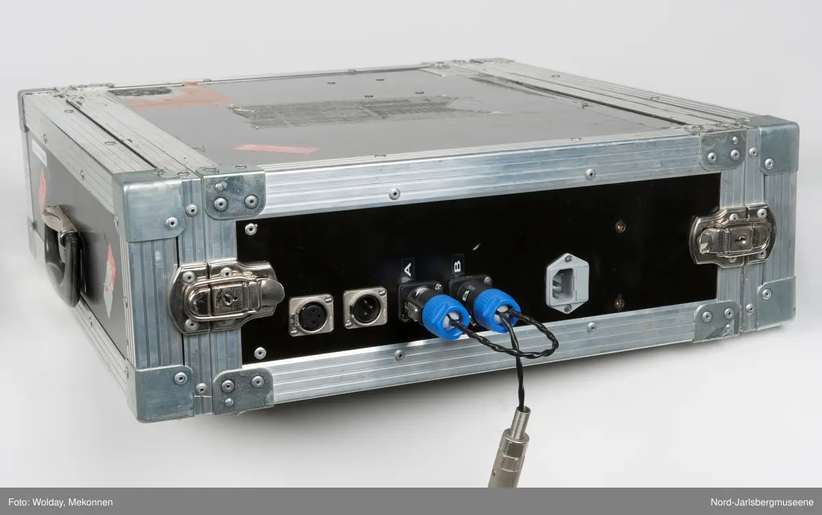 Spesialbygget metallkoffert for audiomåleapparater. Kofferten har åpning på hver ende. På den ene siden finner man måleinstrumenter; to "True Diversity Receiver" og en stor forsterker. I lokket på denne siden er det plass til å oppbevare mindre tilleggsutstyr. Under det andre lokket finner men baksiden av apparatene samt ledninger. Lokket her også plass til ekstra, lange ledninger for kobling til andre apparater. På dene ene langsiden er det tre uttak for koblinger, hvorav en har koblingsledning i.