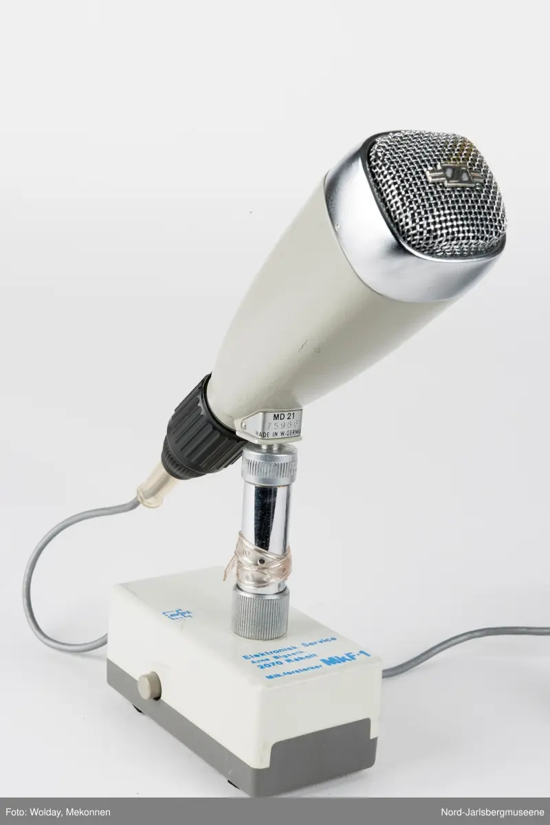 Bordmikrofon montert på en kort stang til en rektangulær fot (forsterker?)med to forskjellige el-kobling til headset?
Selve mikrofonen er kantet konisk med lydhode i blan
kt metall.