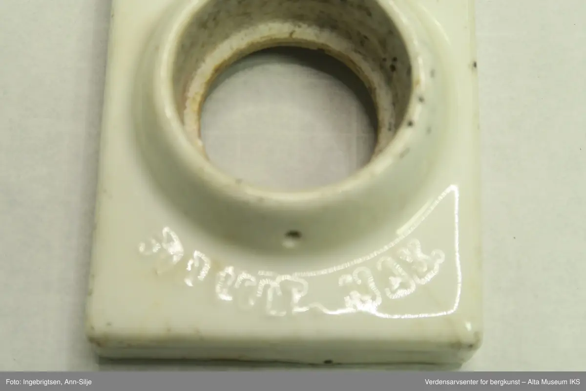 Syv ulike gjenstander som alle har med elektrisitet å gjøre. A) Isolator fra kraftlinja fra Kåfjordverket til Haldde: Rund. B) Sikringsholder: Firkantet, 500 volt max. C) Isolator rund . D) Rektangulær fabrikasjonsnummerskilt fra aggregathuset. E)  3 forskjellige runde sikringer fra aggregathuset (1 stor, 2 små).