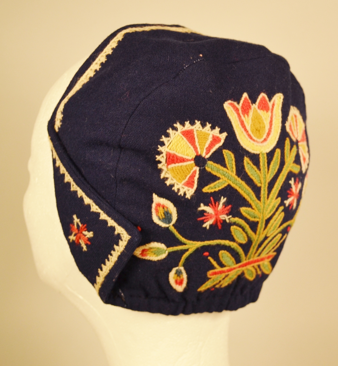 A: Bunad. Blått ullstoff, tynn klede. Har ein brodert bord 5 cm frå nedre kant. Brodert i ullgarn. Borden er 33 cm bred og går rundt same høgde. Det er en grenbord med blomster sydd i plattsøm, kontursting og franske knuter. Overdelen er eit skjørteliv. Rundt skjørtet er det brodert ein bord i kvit snorsøm, fiskebeinsting og franske knuter. Bak 3 stjerner i røde og kvite, foran på skjøtene 4 stjerner. Den broderte kvite borden fortsetter foran og opp og rundt halslinning. Foret overdel med lysgrå silke. 8 sølvringer foran i åpningen for sølvkjede. Denne bunaden har nedsydde folder frå 5 cm og opp til 8,5 cm lengde (ikkje vanleg). Splitten i skjørtet er satt saman med to trykknapper og ein hekte, og overdelen er satt saman i livet med to hekter. Skjørtet er festet til overdelen ti steder. Overdelen går i spiss ned bak.

B: Lue
Maken stoff og broderi som bunad. På pullen er det brodert eit tre med blomster. Same broderi som på overdel er brodert foran på luen. Foret med lysegrå silke. Kyse fasong. H: 17,5 cm, B:18,8 sm

C: Veske
Same stoff og broderi som bunad. Lås i messing. Same for. Låsen påsydd for hand. Låsen er merket: 
JONS KRISTIANSEN
KJOSE
NN
Veske med lås, total lengde: 28,7 cm, bredde: 16,4 cm

D: Skjorte
Kvit bomull med nuppereller. Halslinning 6 cm x 36 cm, skjorta rynket rundt halslinning. Splitt 16 cm ned midt foran. Lengde, 42 cm. Innsatt spjeld under arm 7cm x 7 cm. Vidde arm 42 cm, armlinning 6 cm x 19,5 cm. Total bredde frå arm til arm 153 cm, hvorav bolen er 52,5 cm. Innfelt skulderstykke 8,3 x 15,6 cm. Knapphull for knapper.