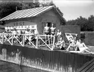 I.O.G.T:s sommarhem Lindesberg på Norrlandet, Gävle. Invigning den 30 juni 1940. Ägt av G.G.I.K. Godtemplarordens flagga är hissad. En mötesplats för ungdomar under krigsåren då Sverige var stängt. Det var fester, lekar, bad och dans på bryggan. Lindesberg låg vid viken mellan Frivy, Lervik och Kullsand. Revs när hamnen byggdes ut. Den som nu minns med glädje och tacksamhet dessa tider är nu 84-åriga Karin.