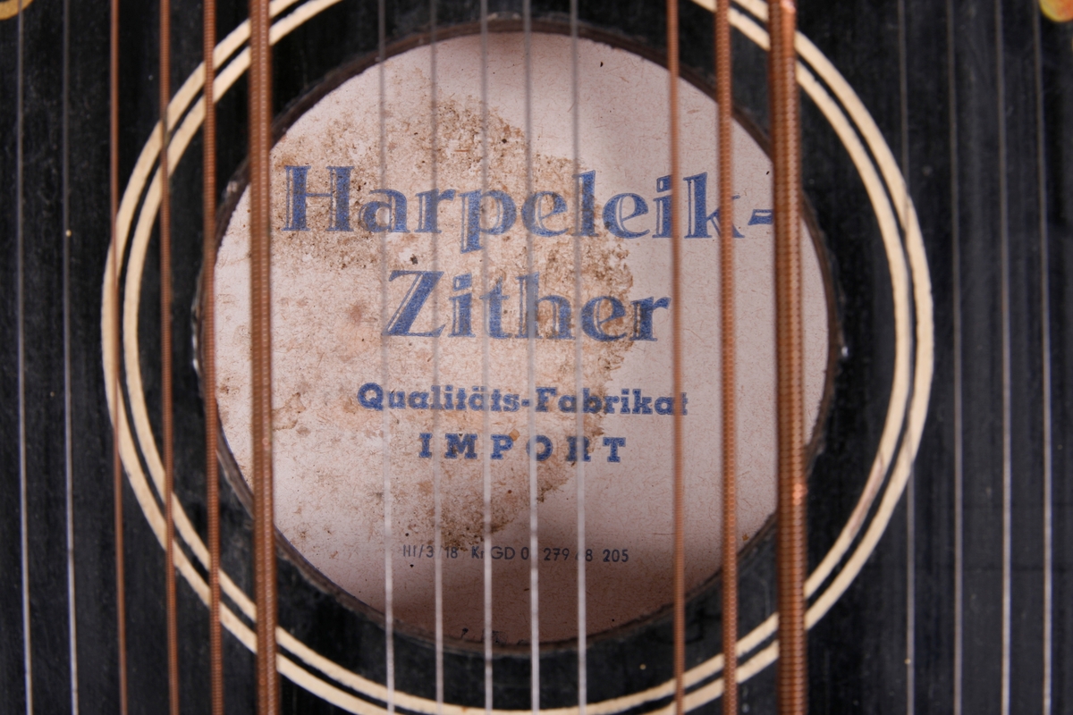 Rektangulær korpus i svartmalt tre. Buet sarg på høyre side, sett forfra. Et anheng er påskrudd nederst på instrumentet, og beskytter strengefestet. Dekor i form av to paralelle linjer går langs ytterkanten på lokket. Stemmestokk og stol i øvre kant. Blomstermotiv på lokket, over lydhullet. Etikett inne i lydhullet; blå bokstaver på hvitt papir. 

Citeren har sju akkorder: F, C, G, D, A, E, H. Totalt 64 strenger. Tersen i hver akkord kan endres ved hjelp av en spake som kan løftes opp. Dermed kan man spille i både dur og moll.