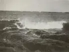 Naturbild på havet med kraftiga vågor som slår mot strandklippor.