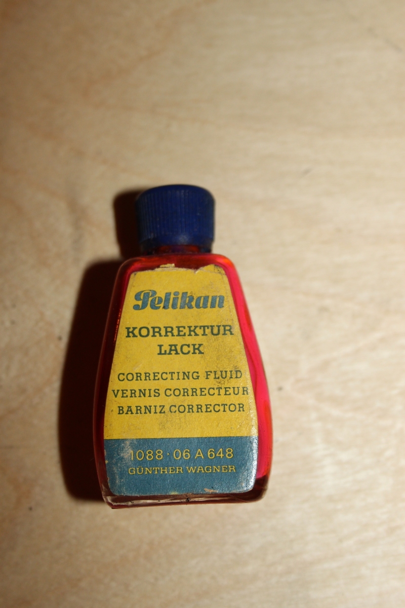 Blekkflaske med skrukork. Glassflaske med papirmerkelapp. Flasken har avrundede former/hjørner. I skrulokket er det festet en pensel.