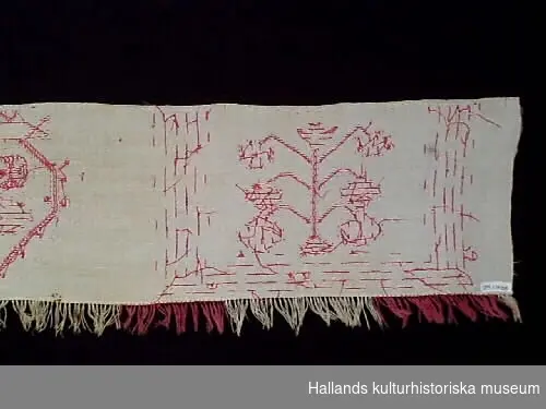 Hängkläde med frans. Vitt med broderier av bomullsgarn i rött och röd och vit frans.