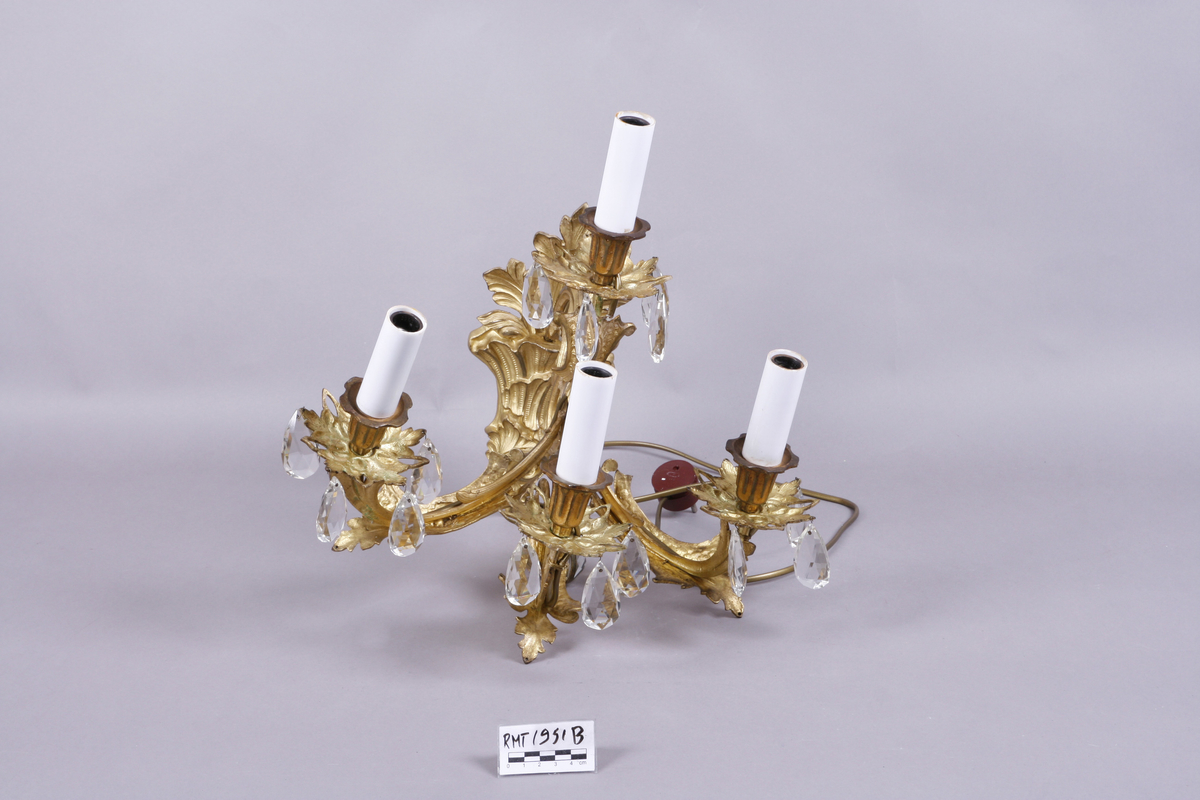Elektrisk vegglampe med tre armer. Støpt metall. Forgyllet. Påhengte fasetterte glassdråper.