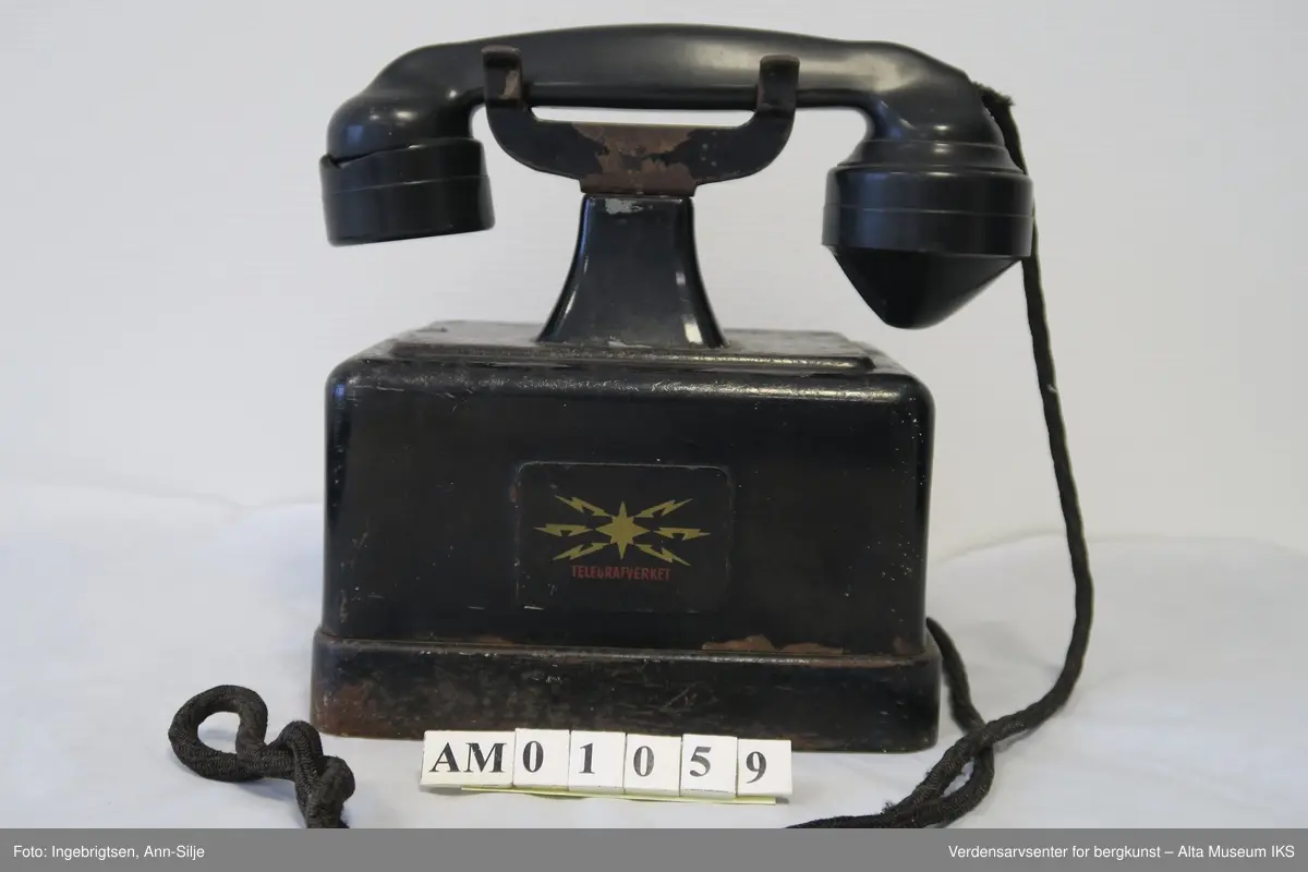 Prismeformet boks med bæreklo på toppen og telefonrør.