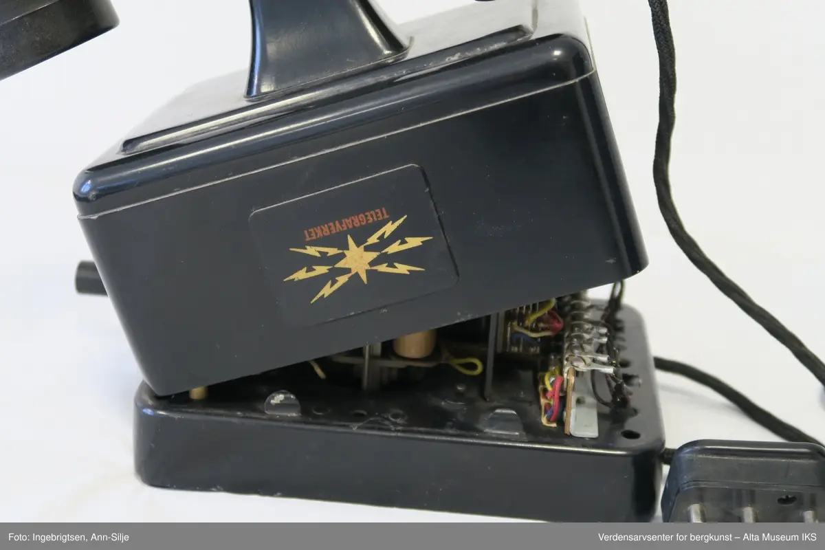 Prismeformet med bæreklo på toppen og telefonrør. Emblem med logoen til Telegrafverket på framsiden av boksen. Boksen er åpnet fra bunnen og er kilt fast slik at det ikke er mulig å lukke den. På baksiden av boksen er det et klistremerke med motiv av Langbein.