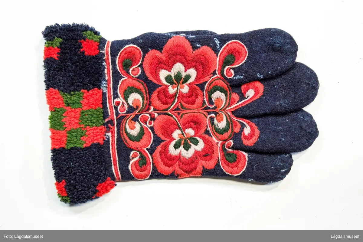 Broderte blomster og motiver på forsiden og tommelen i plattsøm. På håndbaken er det korsstingsbroderte initialer.