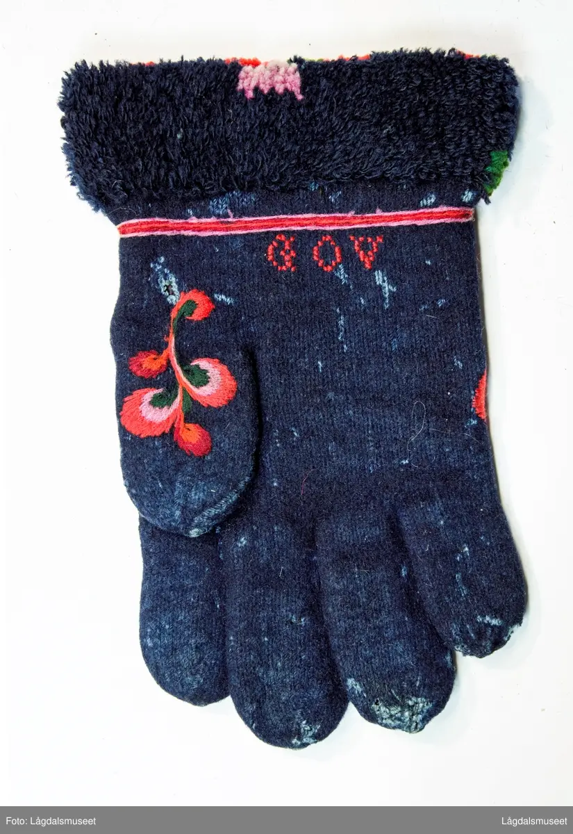 Broderte blomster og motiver på forsiden og tommelen i plattsøm. På håndbaken er det korsstingsbroderte initialer.