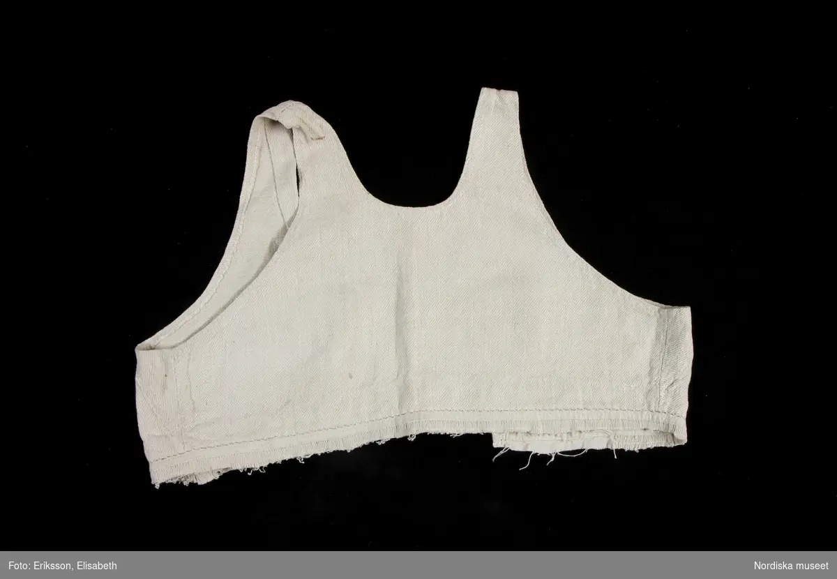 Livstycke, "bod" som varit fastsydd på en linnekjol. Av handspunnet lingarn, blångarn, i treskaftad kypert, "treskäft".  2 raka framstycken och ett ryggstycke, skarvat på axlarna, små kilar i sidsömmarna. Öppet framtill med 3 cm breda knäppkanter på båda sidorna med 2 par hakar och hyskor av mässing. Fåll nedtill med översta delen av kjolen kvar som en ring runtom, där man kan se den täta rynkningen och att kjolen varit av ett tunnare tuskaftat linne.
Denna typ av livkjol kallas i Mora och på Sollerön för vitsärk och användes sommartid. De kunde vävas mer eller mindre grova, och syddes mer eller mindre fint, släta, grovrynkade eller finrynkade och med grövre eller finare liv (bod) alltefter som man avsåg dem till grövsta vardagsbruk eller till helgdagsplagg.
Till fint hade de ofta liv av blommigt tyg men även röda eller gröna vadmalsliv förekom, de enklare hade vitt linneliv med bandgarnering. 
Vitsärkarna kom rätt tidigt ur bruk, sist var det de gamla gummorna, som nyttjade dem. Få är bevarade, ty det var vanligt att kvinnorna sveptes i dem.
Se Ella Odstedt: Folkdräkter i övre Dalarne sid 194-195.

Jfr. hel livkjol från Sollerön inv.nr 211804.
/Berit Eldvik 2007-09-21