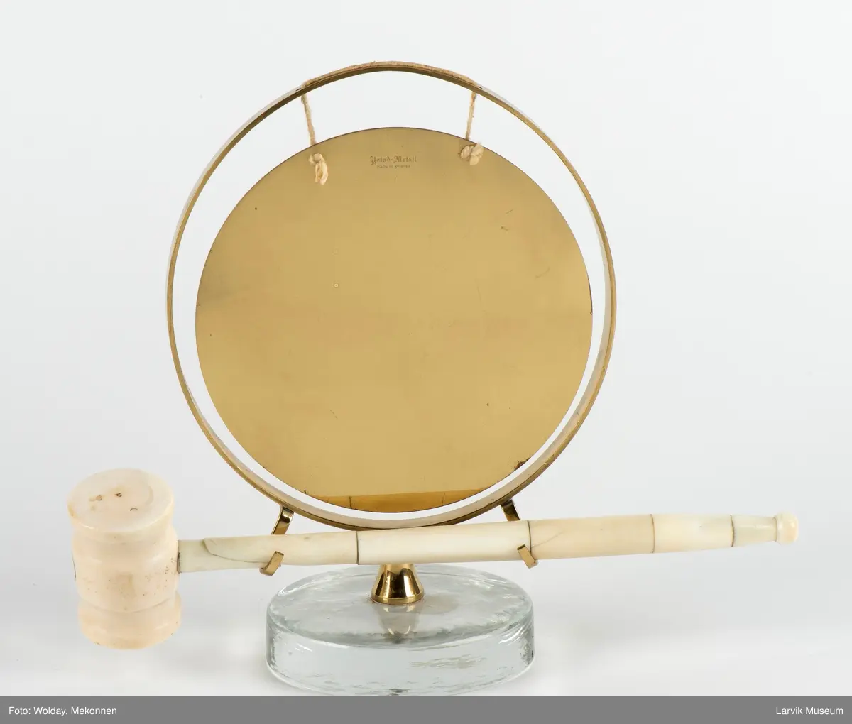 Gongong med klubbe. Festet på en sokkel av glass.