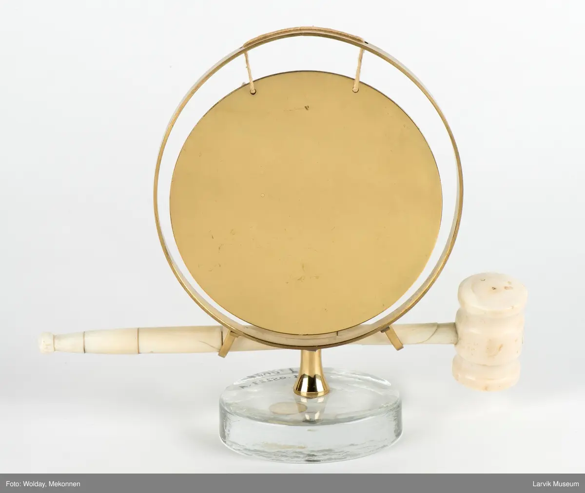 Gongong med klubbe. Festet på en sokkel av glass.