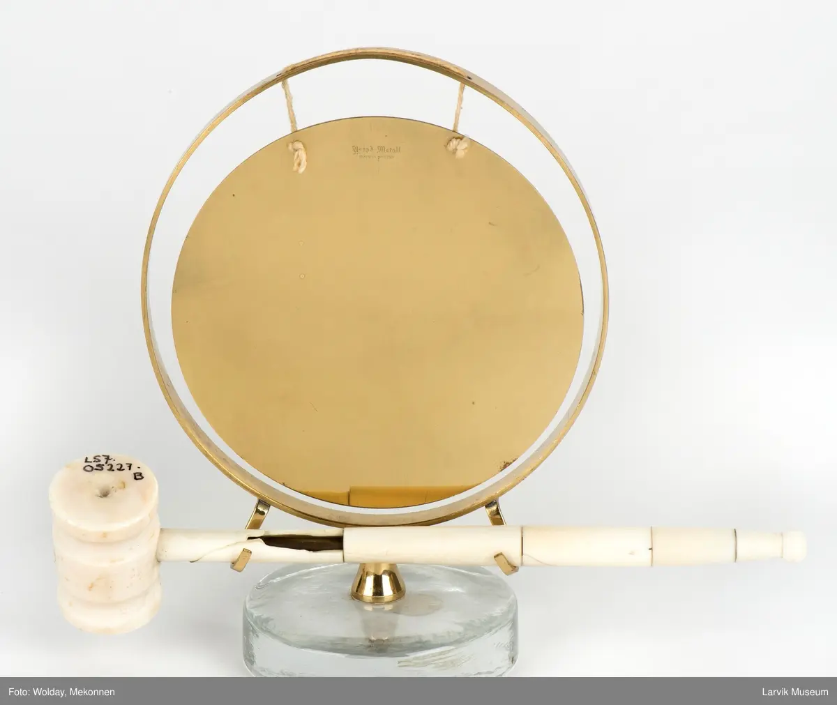 Gongong med klubbe. Festet på en sokkel av glass.