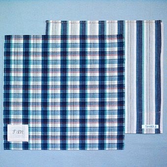 Två vävprover randigt resp. rutigt i bomullsgarn vävt i tuskaft. SH 83:1. Varp i oblekt, blågrönt och tre nyanser blått, inslag i oblekt och två nyanser blått och brunt. Provet har en påsydd tygetikett med texten: T 1279. Mått 365 x 385 mm.SH 83:2. Varp i oblekt, blågrönt och tre nyanser blått, inslag i oblekt. Provet har en påsydd tygetikett med texten: T 1277. Mått 345 x 375 mm.Tygproven är ihopfästade med ytterligare tjugosju prover (inv.nr 77 - 82, 84 - 100) med snören.