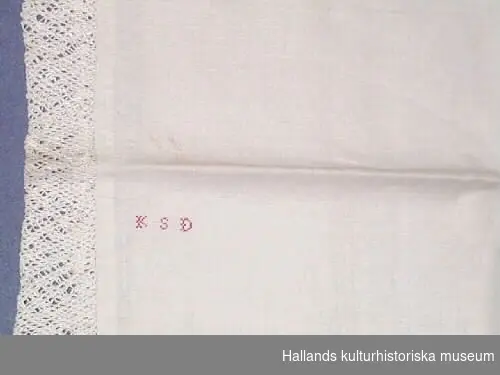 Så kallat putevar med knuten spets. Monogram "KSD", broderat med rött i korsstygn.