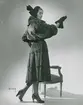 Modell i pälskappa, hatt med rosett, handskar och pumps.