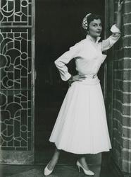 Modell i blus, kjol, pumps, armband och hårdekoration. "Emil