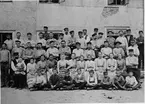 Arbetare vid Gefle glasbruk.
Som nummer två från vänster i översta raden syns buteljuppläggaren August Johannesson.
Flickorna på andra raden nerifrån arbetade som inbärare.
Fotografi från 1890-talet