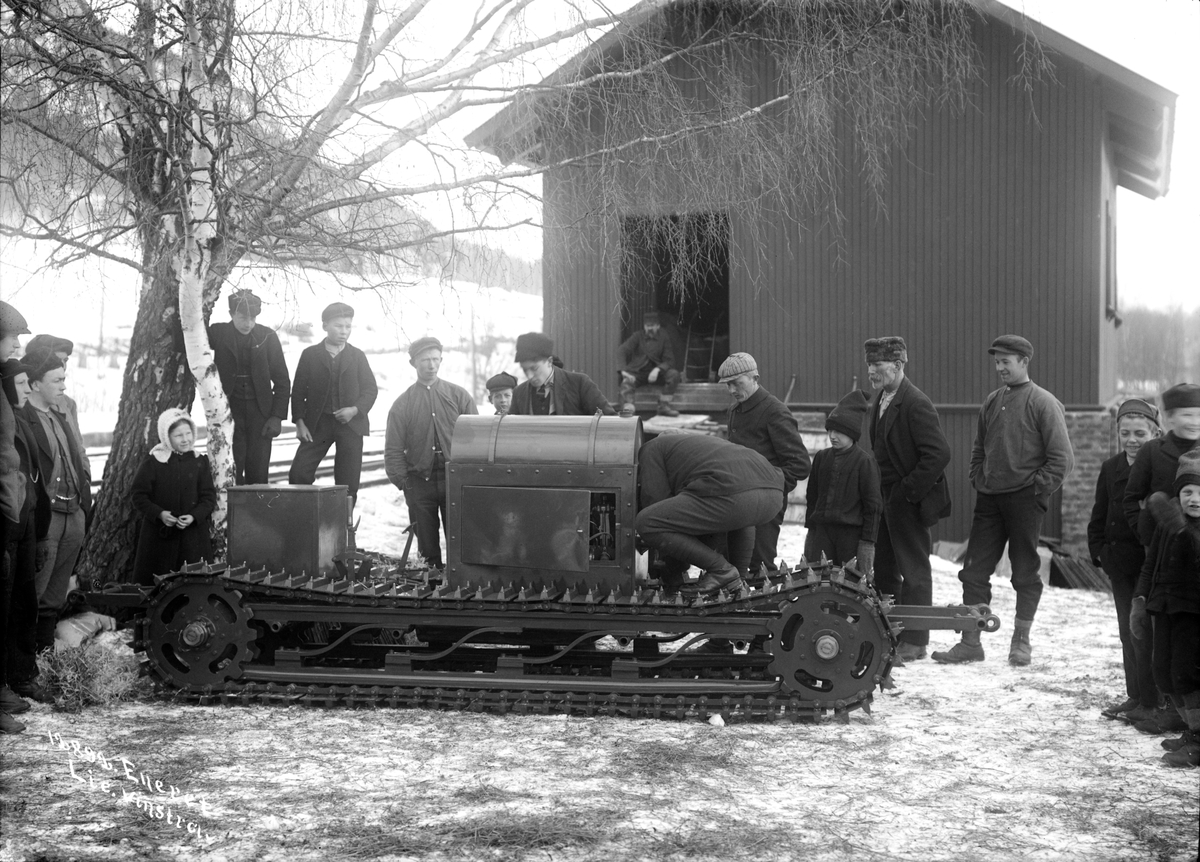 01.03.1910. Motorslage (motorslede). Kapt. Schot (Scott). Motorisert beltekjøretøy, gruppe av personer stående rundt kjøretøyet, uthus.