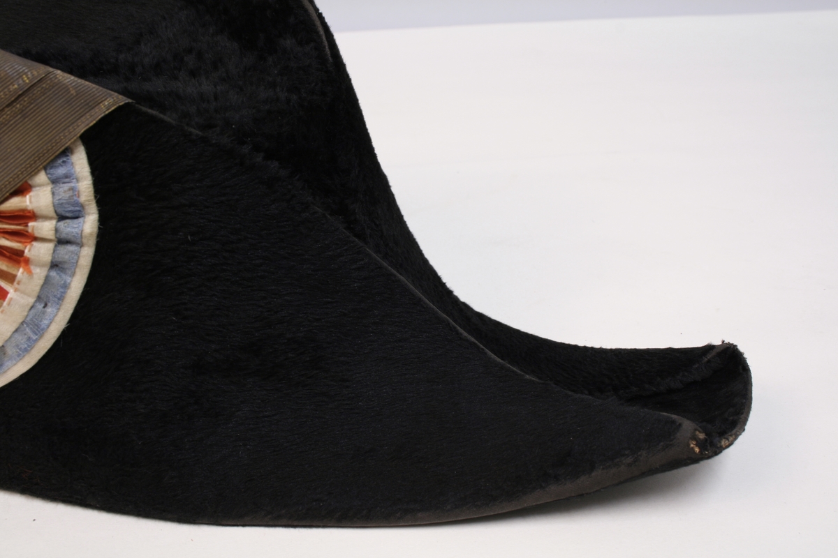 Sort snutehatt med nasjonalkokarde og gullbånd festet med messingknapp med den norske løve.