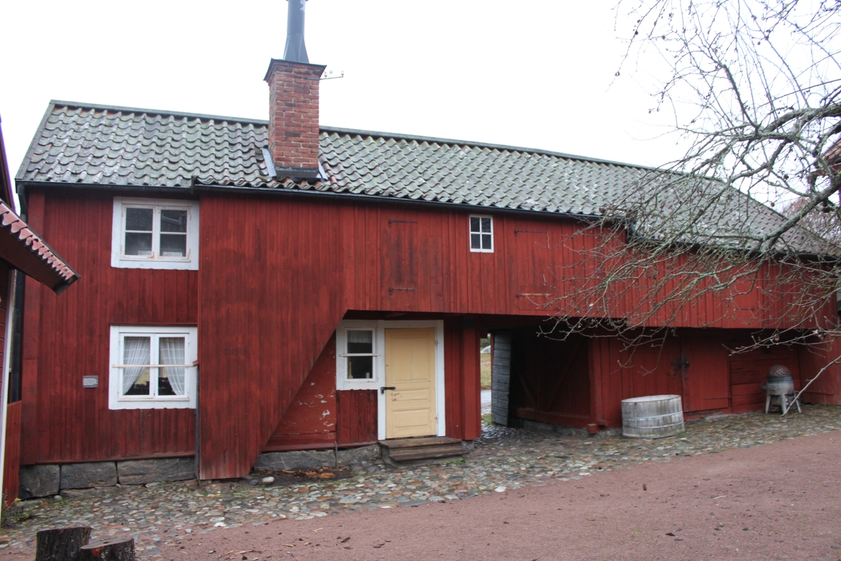 Byggnaden innehåller två bostäder om ett rum och kök samt förråd. Den står på en grund av huggen sten och är uppförd i liggande timmer med utknutar och knutlådor. Byggnadens nedersta våning är delad av ett portlider. Fasaden är delvis klädd med locklistpanel på bostadsdelen och uthusdelen, västra och östra fasaderna. På övervåningen inbyggd svalgång åt väster, täckande nästan hela fasaden, med tre luckor och litet fönster med spröjs. Västra fasaden har rödfärgade plankdörrar och luckor, förutom entrédörren till bostaden som är en gulmålad ramverksdörr. Vid portlidrets östra utfart sitter en svartmålad port av plankor, klädd med liggande panel. Spismuren är synlig i västra fasaden. Tegelskorsten med monterat plåtrör på toppen och plåtkant mot taket. Sadeltak liggande på tre åsar, med höjd del över svalgångens bostadsdel. Taket är belagt medenkupigt  tegel. Nock- vatt- och vindskivor är av trä. Mot väster finns hängrännor och stuprör i plåt.