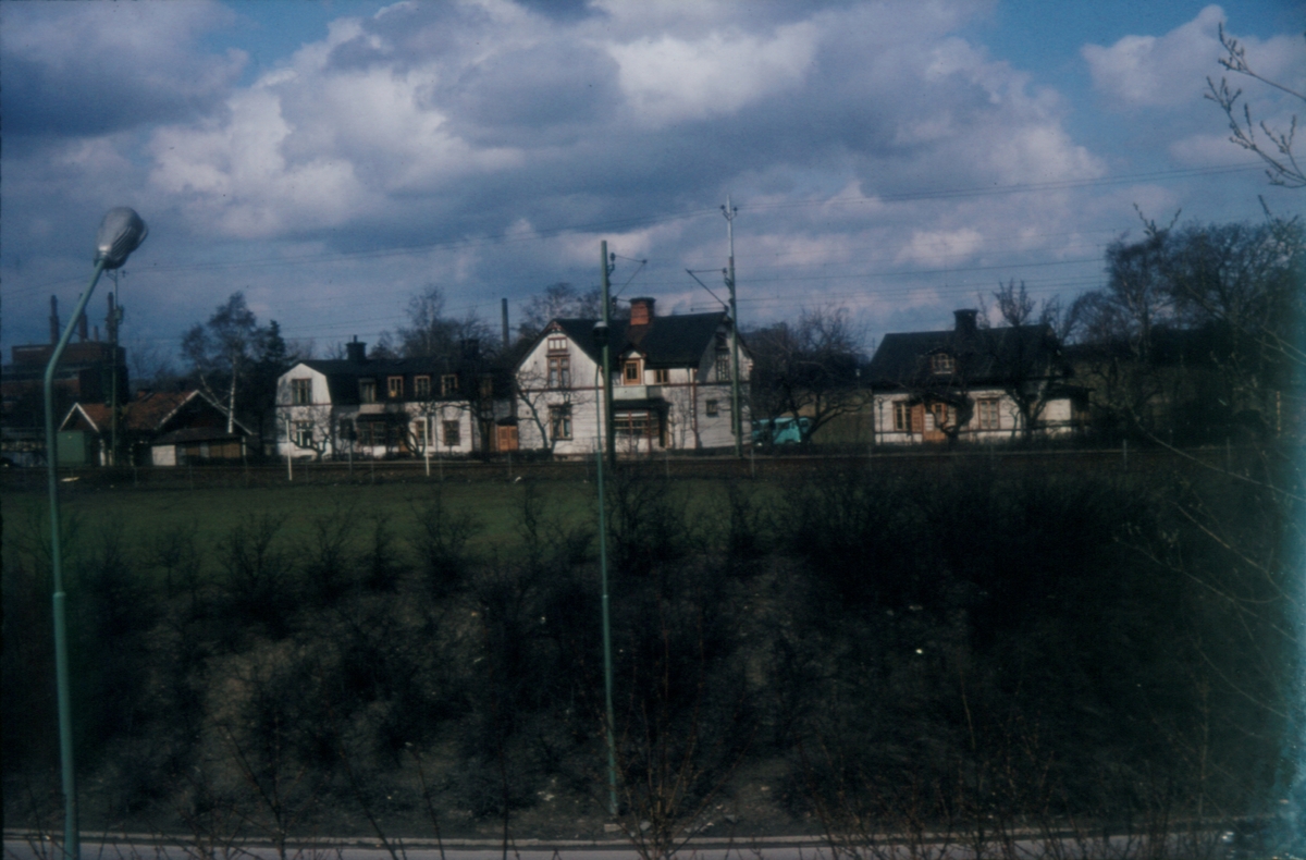 Orig. text: Norrköpingsvägen, stambanan, Björngatan, värmeverket.

Husen ligger på Ladugårdsbacke 4, stadsäga 1752.
De vita byggnaderna revs i februari 1970.