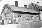 Hunnebergsgatan 23 med en grupp människor framför. 
Enligt en anteckning tillhörde en del av personerna familjen Djerf (känd ifrån Derby).
Livförsäkringsagent Johan Axel Djerf med hustru och fem barn bodde i gården 1912-1924 vilket ger en uppfattning om när fotot togs.