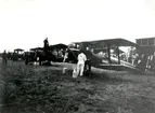 Orig. text: Flygets dag på  flygfältet i Malmslätt. F3 Jaktfalkar iordningställles för uppstigning.

Extern upplysning: Flygplanen på bilden är inte J6 Jaktfalk utan Sk11 Tiger Moth.

Extern upplysning 2025-09-15: Tyvärr är det inga Sk 11 heller (men nära på), det är ett besök från Norge och deras Flyveskole med De Havilland 82 Tiger Moth. Tydlig norsk Haerens Flyvevåpen märkning på rodret. Serienummer ser ut att vara 153 och 157 för de två närmaste.