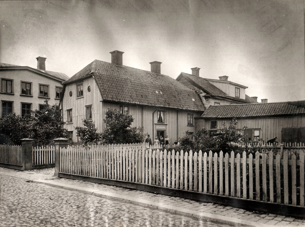 Jungfru Lovisas gård. Gården ses från Klostergatan. Byggnaden uppfördes 1760 av skomakaren Lars Björkman. Vid sekelskiftet 1900 genomgick byggnaden en omfattande upprustning varvid bl a tre takkupor mot gården tillkom. Gården har en lång tradition som privathotell. Byggnaden finns i Gamla Linköping idag.
Bilden är monterad på ett albumblad. Orig. text till bilden: Gården kallades i äldre tider Jungfru Lovisas gård. Smidesmästare G. A. Anderson ägde gården från 1897. Sedan Fru Alma Stillström till 1945. Tillbyggnad med vindsvåning 1898. Personerna å kortet äro: G. A. Anderson, fru Clara Anderson, hennes moder fru Mina Fahlin, fru Alma Stillström, samt Elin och Hanna Anderson.
