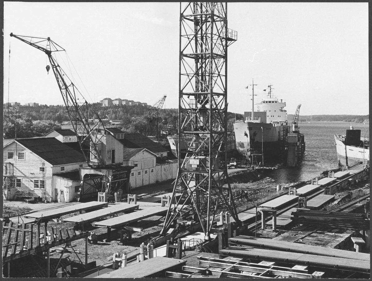 Ekensbergs varv 1970. Vy från plåthallens ö våning mot väster. Till v timmermansverkstaden (med riggarverkstad på övre planet) och den s k nybyggnadskranen, i mitten stapelbädden och en av de s k holländarkranarna, i bakgrunden lastmotorfartygen HEIMATLAND, SALOME och KINGHAM (urspr. HARÖ).