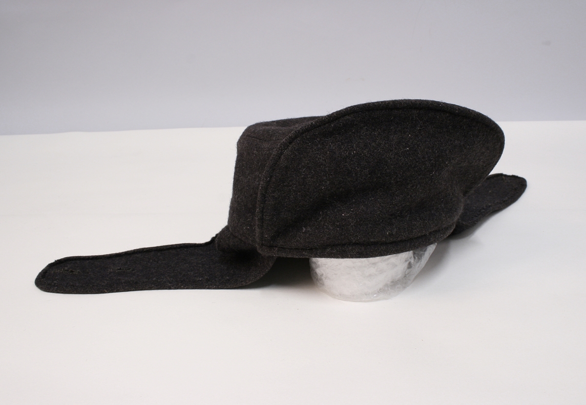 12 glatte messingknapper foran, 3 knapper på hvert av ermenes oppslag. En lomme på hver side, hver lomme med 3 knapper. Gule paspoiler om oppslag, lommeklaffer og knappingen foran.

Beltet har jernspenne med 1 torn. Devisen er fastnaglet. Man kjenner også til fra gamle tegninger av vekteren at beltet har hatt devisen "Ædru og Troe".


Har øreklaffer til å brette ned og kneppe sammen under haken. Foran en rett oppstående skygge.