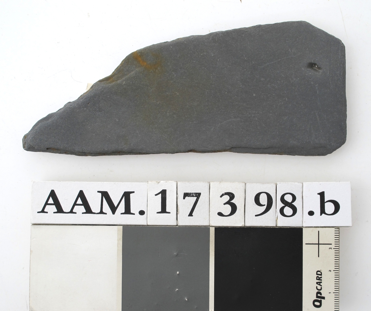 Skifertavle i fire deler .  
a)  17,7 x 8. Femkantet hjørnestykke.  
b)  15 x 6,3. Hjørnestykke med et hakk,  den lengste side er buet. A-b = G 1435.  
c)  16,5 x 5,8. Smalt spisst bladformet. = G 1153.  
d)   Lite skiferstykke. L. 4,8. B. 1,5