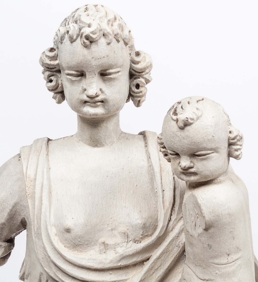 Kyrklig skulptur, trä, staty från gamla korskranket i Heliga Trefaldighets kyrka i Gävle, av Ewert Friis omkring 1665. 

Stående kvinnofigur med naket barn på vänster arm samt stående naket barn vid höger sida. Sistnämnda barn har ett brinnande hjärta i höger hand och kvinnans vänstra hand på sitt huvud. Vänster ben är främst, foten avslagen. Sittande barnets ena ben och andra fot avslagna. 
Fyrsidigt, profilerat postament. 
Gråvit färg.
