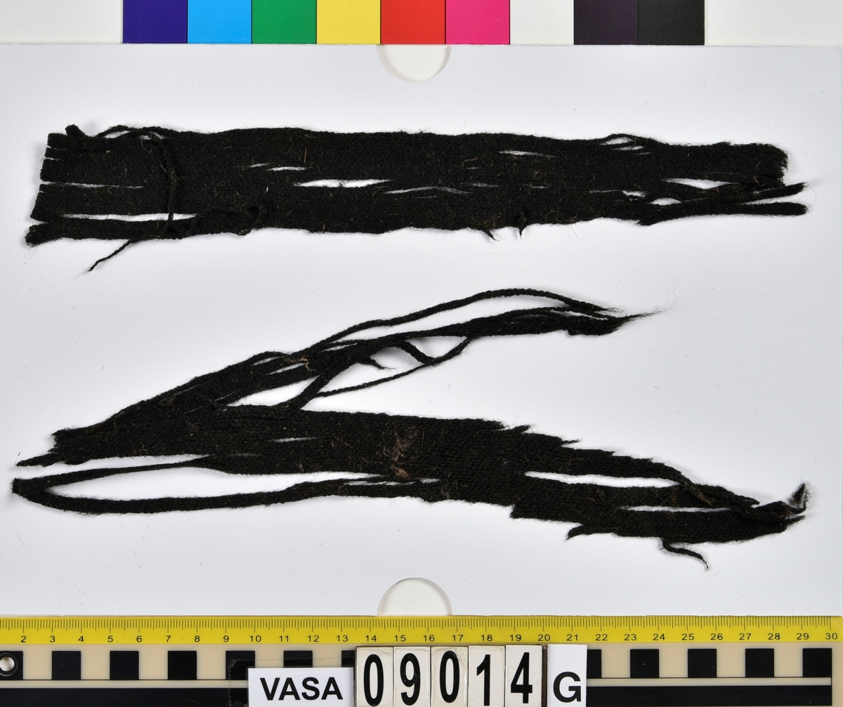 Textildokumentation 2018
Textil, fyndnumret består av mer än 50 st fragment uppdelade på 09014a-h.
Kontextgrupp ÖB20 (övriga fyndnummer i gruppen: 07732, 07762, 09228)
Relaterade fynd: Kontextgrupp ÖB17 och ÖB 18.
.
Fnr 09014a Typnr ÖB20.3:1
Sammanfattning - Ett textilfragment av ull vävt i tuskaft. Färgen är nu mörkbrun, fibrerna varierar i färg vilket tyder på att det är naturfärgad ull. Fibrerna är i vissa partier skadade på ytan och ser därför vita ut. Väven är tunn, jämn och fin och har inga spår av ytbehandling. Fragmentet har tre tillskurna kanter, två av dessa har spår av tre olika sömmar (söm 1: kvicksöm/förstygn). Formen tyder på att det är ett skört till en tröja. Andra delar: Jämför med 07726. 
.
Fnr 09014a Typnr ÖB20.4:1
Sammanfattning - Ett textilfragment av ull vävt i tuskaft. Färgen är nu mörkbrun, originalfärg okänd. I mikroskop ser tyget blåsvart ut. Väven är mycket jämn och slät. I sömsmånen på sida A finns bevarad lugg, på sida B är luggen så välbevarad att bindningen inte syns. Fragmentet har två tillskurna kanter med hål och avtryck av sömmar, även trådrester finns (söm 1: kaststygn - fälld kant, söm 2: ev förstygn - sammanfogande, söm 3: kaststygn - fälld kant). På sida B finns blåfärgad ull och silkesfibrer. 
.
Fnr 09014a Typnr ÖB20.5:1
Sammanfattning - Ett textilfragment av ull vävt i tuskaft. Väven är jämn och tät. En av kanterna är troligen tillskuren, inga sömrester finns. Tyget har inga spår av ytbehandling. På ytan finns en del bastfibrer. Relaterade fynd: Vävens struktur liknar ÖB20.4:1 men tygerna har ändå olika karaktär och detta fragment saknar lugg. 
.
Fnr 09014a Typnr ÖB20.6:1
Sammanfattning - Ett textilfragment av ull vävt i tuskaft. Färgen är nu brun, originalfärg är okänd men möjligen naturfärgad, fibrerna är mycket släta och varierar i färg från brun till nästan svart. Fragmentet är litet och mycket skadat, endast några få bindepunkter återstår vilket försvårar mätningar. 
.
Fnr 09014a Typnr ÖB20.7:1
Sammanfattning - Ett textilfragment av  ull vävt i tuskaft. Färgen är svartbrun, originalfärg okänd men möjligen naturfärgad då fibrernas färg varierar. Inga tydliga spår av ytbehandling. Väven är jämn men garnet är hårt spunnet vilket ger tyget en kypertkaraktär (falsk kypert). Fragmentet har inga tillskurna kanter eller sömmar. På ytan finns enstaka vita silkesfibrer.
.
Fnr 09014a Typnr ÖB20.8:1
Sammanfattning - Ett textilfragment av ull. Fragmentet är mycket litet och dåligt bevarat så bindningen är svår att avgöra, troligen 2/2 kypert. Färgen är svart, möjligen naturfärgad ull då fibrerna varierar något i färg. Tyget har ingen synlig ytbehandling. Garnet är hårt spunnet vilket ger tyget en speciell karaktär. 
.
Fnr 09014b Typnr ÖB17.1:8-11
Sammanfattning - Fyra textilfragment av ull vävt i tuskaft. Färgen är mörkbrun, originalfärg okänd men den bruna tonen slår mot röd. Tre av fragmenten har tillskurna kanter och spår av sömmar. Andra delar, som troligen kommer från samma tröja, är fnr 03261a och d, 09014h samt 09228a. 
Fragment ÖB17.1:9 - Fragmentet har två tillskurna kanter varav den ena har spår av en söm. Fragmentet är troligen sidostycket till en tröja. Den tillskurna kanten har då varit monterad mot tröjans bakstycke och bör ha hört samman med fyndnummer 03261d, vilket är ett bakstycke till en tröja.
Fragment ÖB17.1:10 - Fragmentet är mycket skadat men är troligen av typen ÖB17.1. Formen är densamma som för del av fragment ÖB17.1:9 och kan därför vara en dubblering av detsamma, alternativt det motstående sidostycket.
.
Fnr 09014c Typnr ÖB20.9:1-19
Sammanfattning - Nitton textilfragment av ull vävt i tuskaft. Färgen är brun, originalfärg okänd. Sida B har en kort tät lugg som döljer bindningen. På sida A finns ingen lugg och bindningen är synlig. Fjorton av fragmenten har tillskurna kanter och sömmar. Tre av fragmenten har sydda knapphål. Flera fragment är dräktdelar, till exempel finns en fragmentarisk krage. På ytan på flertalet fragment finns fibrer i flera klara färger, till exempel rosa, röd och blå. Vita fibrer finns i stor mängd, kan vara recenta.

Fragment ÖB20.9:1 - Fragmentet har flera tillskurna kanter med avtryck och hål efter olika typer av sömmar (söm 1: ev. sammanfogande, söm 2: kaststygn - fåll, söm 3: kaststygn - sammanfogande, söm 4: kaststygn - sammanfogande, söm 5: osäkert, söm 6: osäkert), trådrester finns. Kanterna och sömmarnas karaktär gör att sida A bedöms vara plaggets rätsida/utsida. Några hål som ej är stygnhål men kan vara original finns. I fragmentet sitter fast två stycken silkestrådar (söm 7: silkestråd med knut, fäst i tyget, söm 8:  silkestråd med ögla, fäst i tyget). Det är samma typ av tråd som knapphålen på fragment ÖB20.9:2 är sydda med. På sida A finns ett område med extra mycket korrosion och även en långsmal vitaktig avlagring.

Fragment ÖB20.9:2 - Fragmentet har inga bevarade tillskurna kanter, dock finns en någorlunda välbevarad rad med knapphål. Samtliga knapphål är trasiga i ena sidan så deras ursprungliga storlek går ej att avgöra. Knapphålen är sydda med knapphålsstygn i silkestråd och sitter med 13-15 mm mellanrum (c/c mått). Det tvärställda tränsen består av ca 10 stygn och syns ej på sida B, tränsens knutar sitter vända från knapphålet. På sida B anas rester av bastfiber under knapphålsstygnen, troligen från en dubblering av tyget eller ett foder. 

Fragment ÖB20.9:3 - Fragmentet har fyra stycken knapphål, varav ett är helt. Knapphålen är skurna på skrådden. Eventuellt finns spår av en söm längs en del av kanten. Knapphålsstygn och trådrester är mycket fragmentariska.

Fragment ÖB20.9:4 - Fragmentet har tre stycken knapphål.  Knapphålen är sydda med knapphålsstygn i silkestråd. Knapphålens längd är 19-20 mm och de sitter med 18-22 mm mellanrum (c/c mått). Eventuellt är fragmentets ena kant en sömsmån, kan ha varit monterad mellan andra tyglager (kanten har avvikande färg). Under knapphålsstygnen på sida B finns rester av annat material, eventuellt bastfiber. Bastfibrer finns också utspridda över ytan på sida B, kan vara rester av en dubblering till tyget eller ett foder, se fragment 9:2. På sida A finns avlagringar och korrosion. 

Fragment ÖB20.9:5 - Fragmentet har bristningar i tyget som ser ut som knapphål, dock finns inga rester av stygnhål eller tråd. Fragmentets ena kant är troligen en sömsmån, kan ha varit monterad mellan andra tyglager (kanten har avvikande färg). Enstaka spår av söm och tråd finns längs kanten (söm 1), dessa är mycket otydliga. På fragmentets andra (mycket trasiga) kant finns ett mycket tydligt stygnhål. Fragment 9:4 och 9:5 ser ut att kunna höra ihop, dock går trådsystemen åt olika håll så det är inte fallet.

Fragment 9:6-9 - Till det stora fragmentet 9:6 hör det lilla lösa fragmentet 9:7. I fragment 9:6 sitter två fragment fastsydda, 9:8 och 9:9. De sammansydda fragmenten har tre tillskurna kanter och spår av minst fem sömmar (söm 1: kaststygn, söm 2: förstygn el. liknande - sammanfogande, söm 3: kaststygn, söm 4: sammanfogande, fäster ihop 9:6 med 9:8 och 9:9, söm 5: två stygnhål), trådrester finns. Det är troligt att 9:8 och 9:9 är delar av samma tillskurna bit, och att den utgjort en dubblering till 9:6 (inklusive 9:7). Den tillskurna formen ser ut att vara en krage. Fragmentet skulle då vara en halv krage, bevarad från framkant till nästan mitt bak. På sida A finns en beläggning på delar av ytan. På sida B finns en mängd fibrer i klara färger: blå, vit, rosa, tegelröd, orange, karminröd, grön, mörkgul och grå. fibrerna ligger ytligt med nästan samtliga sitter delvis fast i tygets lugg eller har en eller båda ändar nere i vävens bindning. Fibrerna bör därför vara ursprungliga. Sida A har en mindre mängd av nämnda fibrer, mest förekommande på ytan av fragment 9:8 och 9:9.

Fragment ÖB20.9:10 - Fragmentet har två tillskurna kanter. Dessa är invikta mot sida B som en 6-7 mm bred fåll som är fastsydd med kaststygn, trådrester finns (söm 1 och 2). Fragmentet kan vara ett skört till en tröja. På båda sidors yta finns fibrer i klara färger: grå, ljusblå, orange, orangebrun, vitgul, blå svart, vit, röd, korallröd och rosa.

Fragment ÖB20.9:11 - Fragmentet har tre tillskurna kanter med sömmar. Två av kanterna är invikta och fastsydda mot sida B, som fållar (söm1: kaststygn - fåll, söm 2: kaststygn - fåll). Stygnen går ej igenom till sida A men sömmen syns som bucklor i fragmentets yta. Söm 3 längs den tredje kanten har troligen varit en sammanfogande söm sydd med kaststygn. Stygn och trådrester finns bevarade från samtliga sömmar. Under fållen vid söm 1 finns ett litet fragment av en annan textiltyp. Troligen ursprungligen en dubblering eller liknande. Fragmentet är ca 10x5 mm stort och har fått typnummer ÖB20.16:1. På ytan på sida B finns enstaka bastfibrer.

Fragment ÖB20.9:12 - Fragmentet har två tillskurna kanter med sömmar (söm 1: ev kaststygn, söm 2: osäker). Vid söm 2 är sömsmånen vikt mot sida B. Vid söm 1 är kanten inte vikt. Fragmentet har samma form som ÖB20.9:6, "kragen".

Fragment ÖB20.9:13 - Fragmentet har två tillskurna kanter med sömmar (söm1: sammanfogande, söm 2: osäkert). De två övriga kanterna är eventuellt också de tillskurna men spår av eventuella sömmar är för otydliga. Enstaka fibrer med klara färger (rosa, blå, vit) finns på båda sidor, fler på sida B. Vid söm 2 finns på ett ställe en fiberknippa som kommer upp ur vävens bindning, kan vara rester av en tråd och är eventuellt halsplat silke. 

Fragment ÖB20.9:14 - Fragmentet har en tillskuren kant med söm (söm1: ev sammanfogande). I stygnhålen finns rester av tråd.
.
Fnr 09014c Typnr ÖB20.10:1
Sammanfattning - Ett textilfragment av ull vävt i tuskaft. Färgen är brun, originalfärg okänd. Sida B har en kort och tät lugg, bindningen syns bara på sida A. Längs ena kanten finns tre stycken tydliga hål. Hålen är gjorda med ett verktyg som skär av fibrerna snarare än tränger undan dem.
.
Fnr 09014c Typnr ÖB20.16:1
Sammanfattning - Fragmentet är mycket litet och sitter inuti den invikta fållen på fragment 09014c ÖB20.9:11, det sticker bara fram någon millimeter. Fragmentet är mycket skört. Bevarandegrad och storlek gör mätningar svåra. Det är olika garn i trs 1 och trs 2. Sida B är täckt av en lugg, på sida A syns bindningen, om än fragmentariskt.
.
Fnr 09014d Typnr ÖB18.16:2-8
Ej dokumenterad
.
Fnr 09014d Typnr ÖB20.11:1-2
Ej dokumenterad
.
Fnr 09014e Typnr ÖB20.12:1-4
Sammanfattning - Fyra textilfragment av ull vävt i tuskaft. Färgen är brun med inslag av täckhårsfibrer i en mörkare brun färg, originalfärg okänd. Fragmenten är mycket fragmentariska med trs 1 bättre bevarat än trs 2. Enbart på en del av fragment ÖB20.12:1 finns trs 2 samt bindningen bevarad. Utspridda över tygets yta finns grova bastfibrer samt korrosionsfläckar. 
.
Fnr 09014f Typnr ÖB20.13:1
Sammanfattning - Ett textilfragment av ull vävt tuskaft. Färgen är mörkbrun, fibrerna varierar mellan ljus och mörk brun. Originalfärg okänd, möjligen naturfärgad ull. Garnet är hårt spunnet vilket ger väven en särskild karaktär, sida A har en mer strukturerad ytan än sida B. Fragmentet har inga tillskurna kanter. På sida A finns enstaka röda och gulgröna silkesfibrer, samt bastfibrer. På sida B finns enstaka blå, vita och rosa silkesfibrer.
.
Fnr 09014g Typnr ÖB20.14:1-3
Sammanfattning - Tre textilfragment av ull och bastfiber vävt i tuskaft. Färgen är beige för bastfibern (trs 1) och svartblå för ullen (trs 2). Trs 2 är mycker grövre än trs 1. Trs 1 är nästan helt försvunnet. Två av fragmenten har tillskurna kanter och ett har spår av en sömsmån. På ytan av fragmenten finns en stor mängd bastfiber samt en vit/rosa tuss med silke. På fragment 14:2 finns några intensivt blå ullfibrer.
.
Fnr 09014h Typnr ÖB17.1:12-13
Sammanfattning - Två textilfragment av ull vävt i tuskaft. Färgen är brun, originalfärg okänd. Det större fragmentet är tillskuret och har spår av sömmar. Fragmentet är en ensömsärm med sömmen placerad mitt bak på ärmen. På ytan finns stora rostfläckar. Andra delar: Hör troligen (trots färgskillnad) till skelettet Beatas tröja, se fnr 03261a-d, 09228a, 09014b och h.