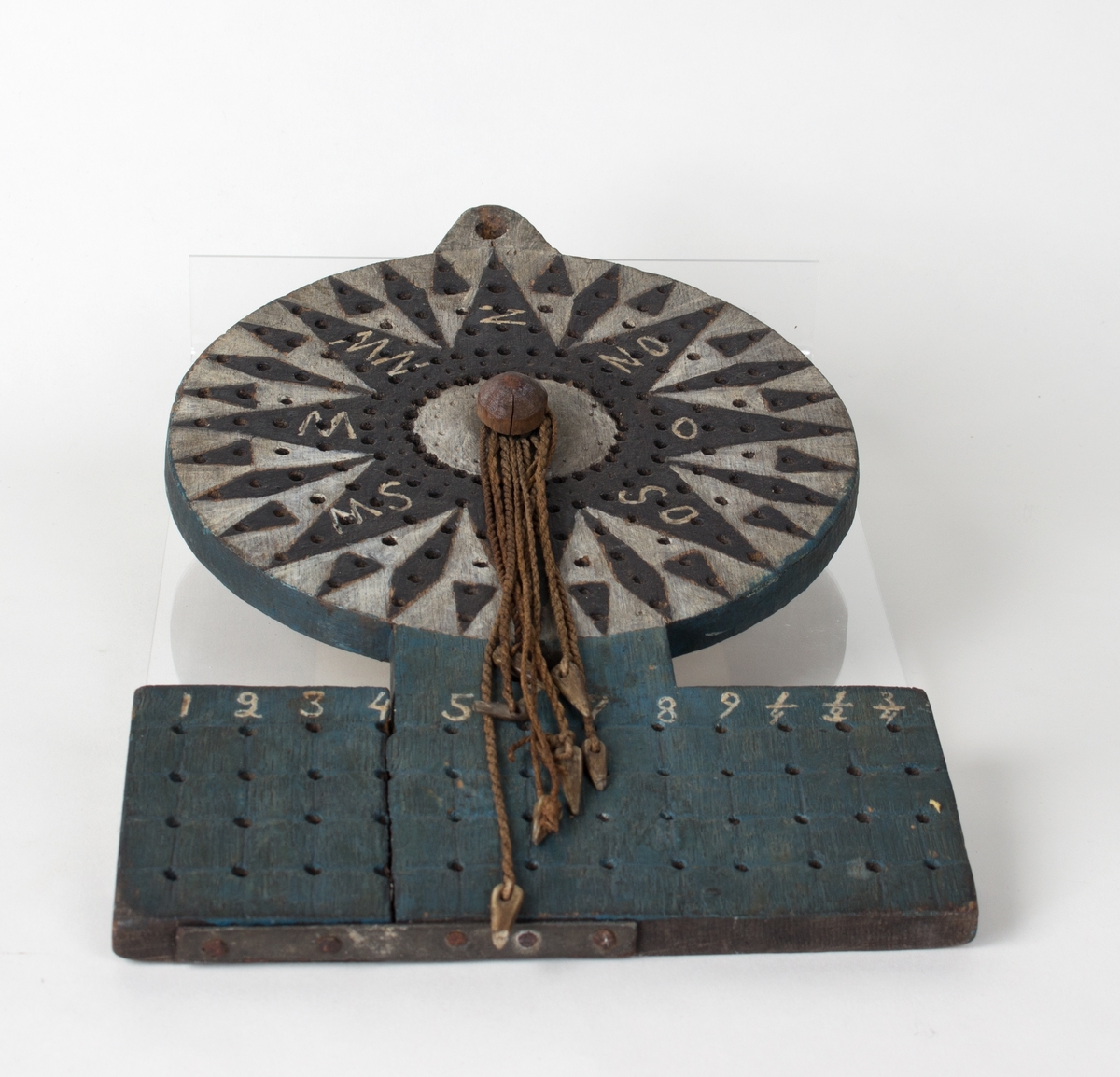 Flat treplate med hull og små bensplinter festet i tau til å loggføre posisjon.