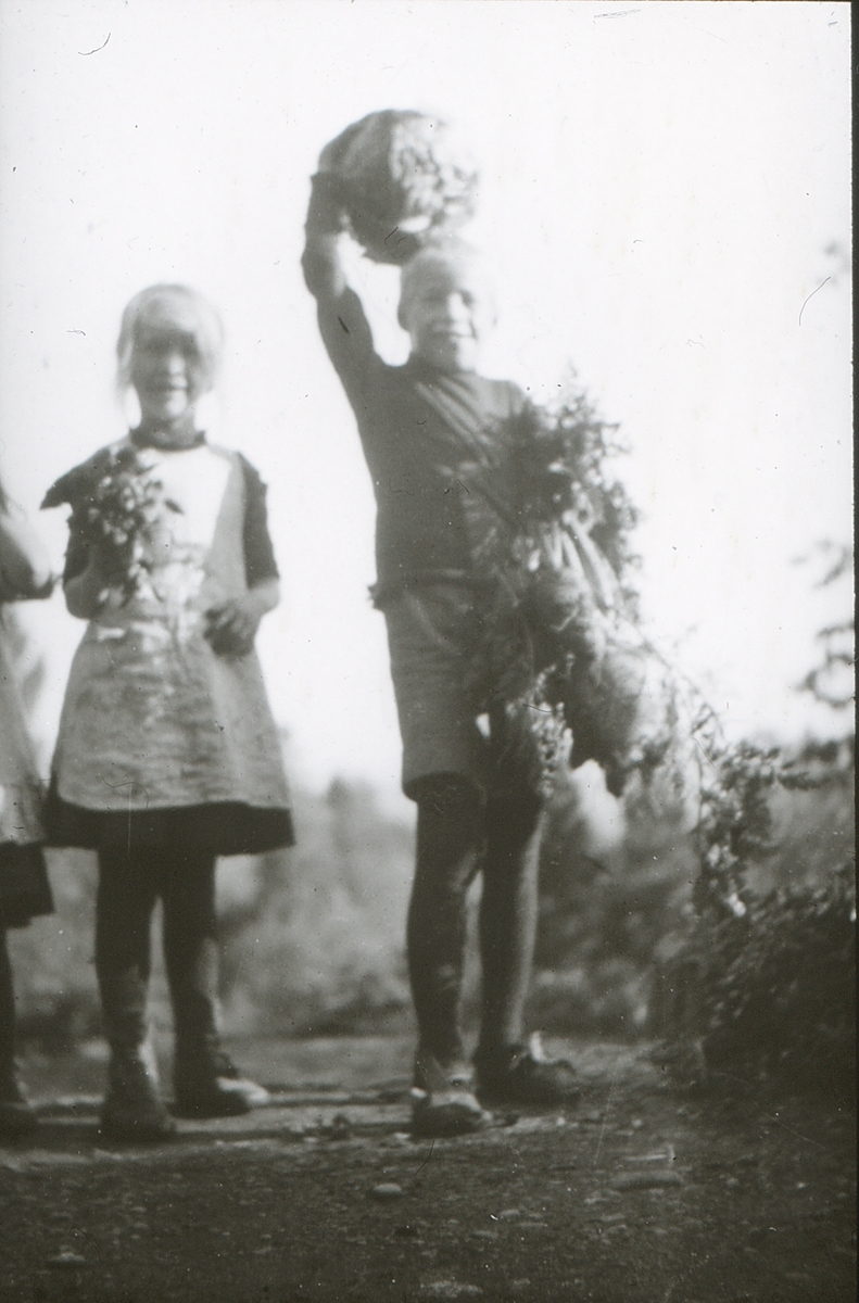 To barn, Per og søsteren, med blomsterbuketter.