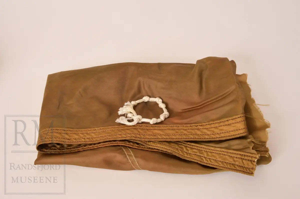 a. Mørk blå kjeledress/ overall med flyvermerke. Militær type. b. Mørk blå lue, berret med H7 luemerke festet og norske farger på bånd. c. Armbind med norske farger. d. Bandolær i lyst brunt lær, messinghemper og spenner. e. Trekantet halstørkle skåret ut av fallskjermstoff (mosegrønn), bit av fallskjermsnor brukt som knyting