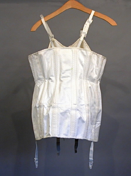 Korsett med snörning framtill. Fyra strumpeband. Material: Textil, ull, bomull, syntetmaterial.