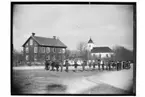 Lännäs skola och Lännäs kyrka.
Tvåvånings skolbyggnad, skolbarn i ring på skolgården. Kyrkan i bakgrunden.
Beställningsnr: LS-102.