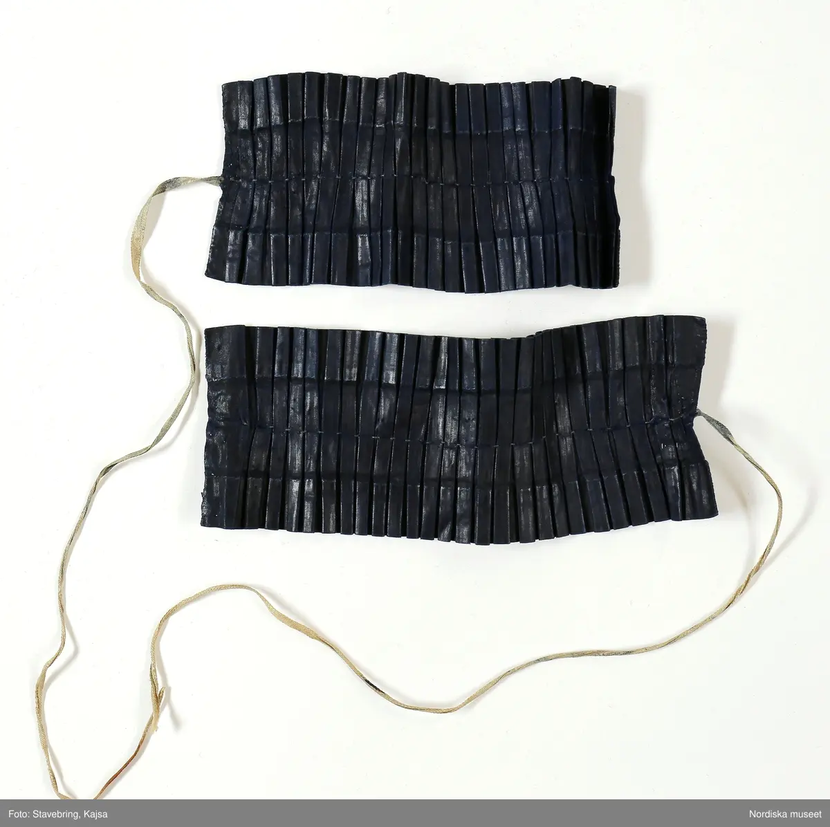 Huvudliggaren:
"Hollands draegt fr. Köpenhamn
Bestående af:
a) Kafetröje med Spaender [tillägg i blyerts.] skall vara kravetröje - 30 kr [spännet ommärkt till e+ 2011-03-08]
Spännet märkt: M.H.P.D.
b) Skjört - 28 kr
c) Forklaede med spaender - 30 kr
d) Haette med tillbehör och Haandstycke - 6 kr
e+) [spännet ommärkt till e+ 2011-03-08] Spännet märkt: M.H.P.D.
Ink. ss 20.087 [=ink. hos fru m. Wildschiödz i Köph. ss 20.001 [= gm (genom) dr A. Hazelius i Stockholm.]]- 94 kr. Under hösten 1877."
