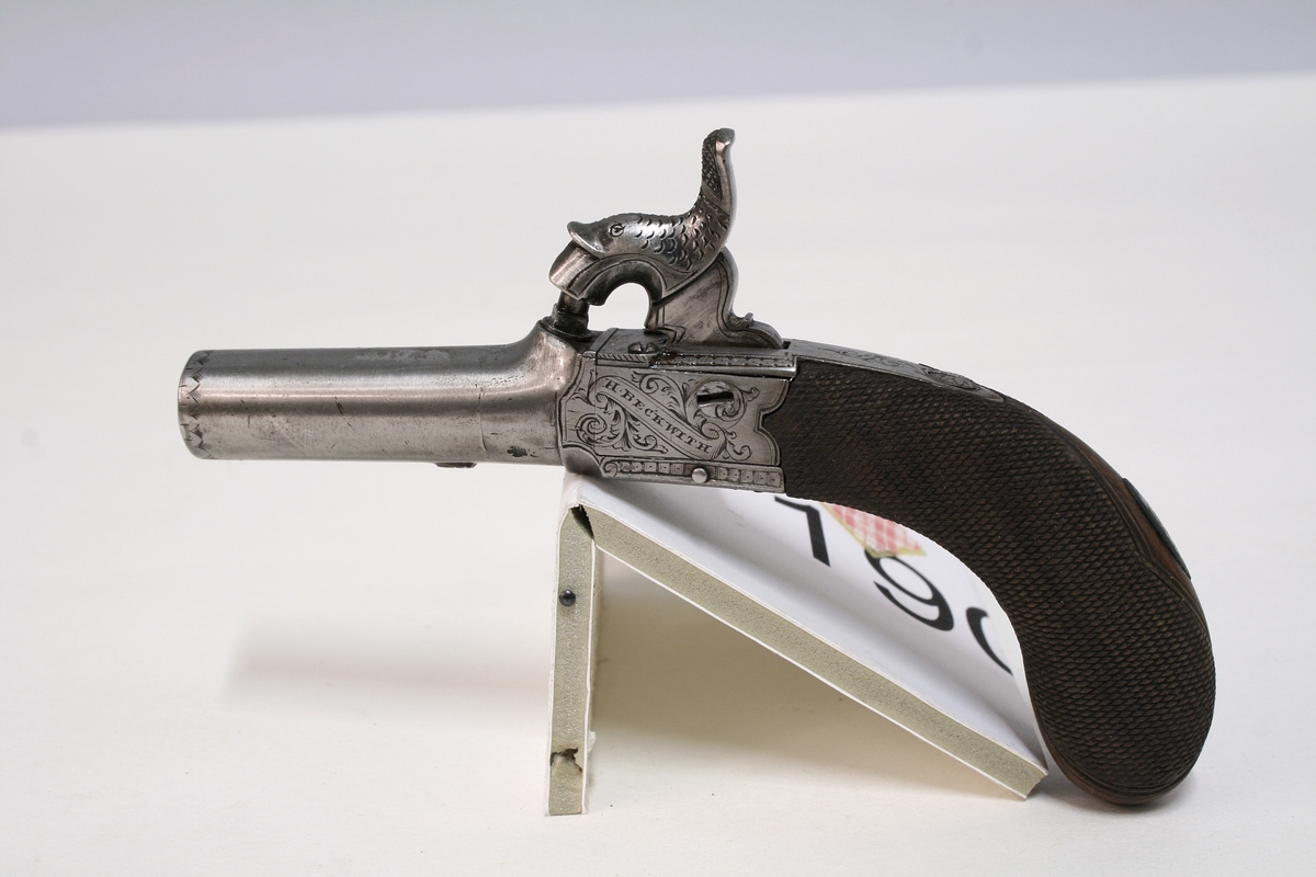Revolver i "cased set", bestående av revolver (Pepperbox), en enkeltløpet perkusjonspistol samt diverse verktøy, alt liggende i mahognykasse. Bestandelene er følgende: 

KASSE av mahogny, 36,6 x 18,6 x 6,6, cm og er forsynt med lokk som har to mesinghengsler i bakkant. På forsiden er det lås med medding nøkkelhullbeslag på forsiden. Nøkkel av jern, ca. 2,9 cm lang. Midt på lokket er det et rundt messingskilt med profilert kant. Skiltets diameter er 3,8 cm. Kassen er indelt i 11 rom hvorav tre er forsynt med lokk med små, hvite gripehåndtak, runde, knappformede med diameter 1,05 cm. Alle rom er trukket med grønn filt. På lokkets innside er klebet produssentens merkelapp.

REVOLVER. Såkalt "Pepperboks". Et revolverende kammerstykke hvor hver kammer utgjør en selvstendig pipe, en forløper for de senere revolveremed kort tønne og langt løp. Kammerstykket (tønne) er 10 cm langt, hver løp har et kaliber på litt underkant av 10 mm. I bakkant er pipene forsaynt med pistong. På utsiden er pipene ca, 1,2 cm fra pistongene, merket fortløpende med nummer 1 - 6 . Mellom pipene er kammerstykket merket vekselsvis med kronet CP og V. Revolveren har overliggendeslaghane med gravert blomsterranke motiver. Bakenfor hanen er det en bevegelig sikringsfløy. Sideblikkene er prydet med graverte blomsterranker,det venstre sideblikket er markert "W.A. BECHWITH LONDON". Avtrekksbøylen er prydet med blomsterranke motiver. Grepsplater av mørkebrunt tre som er filt i rombemønster. Kolbekappen et oval og svakt buet , er kantet med en smal bord og har i midten et gravert, rundt lokk innenfor hvilket er et lite rom for kuler og fenghetter. Grepet har et lite firkantetntommeskilt med brutte hjørner. Alle beslag er av stål. 

PISTOL. Enkeltløpet, total lengde 13,2 cm. Pipen har et kaliber som revolveren. Pipen er 5,4 cm lang og er stemplet med kronet CP og V. Slaghanene står midt oppå pistolen, stikkende opp mellom sideblikkene. Hanen har skjellmønstret dekor og er forsynt med et par øyne. Når hanen spennes, felles en avtrekker fram under under pistolen. Sideblikkene er dekorert med blomsterranker. Den høyre sideblikket er merket "LONDON" og det venstre "H.BECHWIT ", Grepet er av tre,mørkebrunt og er filt i rombemønster. På grepet sitter et ovalt tommeskilt. 
KRUTTFLASKE. Av messing, 11,4 cm lang, flaskeformet, noe flattrykt mot den nedre delen hvor  det vider seg ut i bredden. Festeskrue og fjær for lukkemekanisme er av stål. 
LADE7PUSSESTOKK. av gulfarget med  et 4,6 cm riflet mesinghode. Total lengde 17,6 cm. Vekt.: 14g. 
KULETANG. Av jern, 8,6 cm lang, merket "1". Vekt: 45 g. 
KULETANF. Av jern, 11,5 cm lang, merket "82". Vekt: 44 g. 
PISTOLNØKKEL. For fjerning og innsetting av pistonger på revolveren. 11,3 cm langt og med sortlakkert treskaft. Vekt. 17 g.