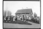 Lillkyrka skola, skolbarn med lärare.
Skolbyggnad i bakgrunden.
Fröken Mina Nyholm