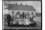 Rinkaby skola, skollärare A. Höggren och 23 skolbarn.
Envånings skolbyggnad i bakgrunden.