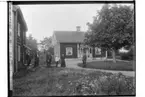 En och en halvplans bostadshus med veranda, snickarglädje, en flygelbyggnad, tvåvånings enkelstuga, timrad.
6 personer på gårdsplanen.
Karl Johan Eriksson