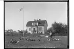 En och en halvvånings bostadshus med frontespis, balkong, veranda och brutet tak.
4 personer framför huset.
Anders Adrian Asplund, Vasstofta 6. Huset byggt 1911.