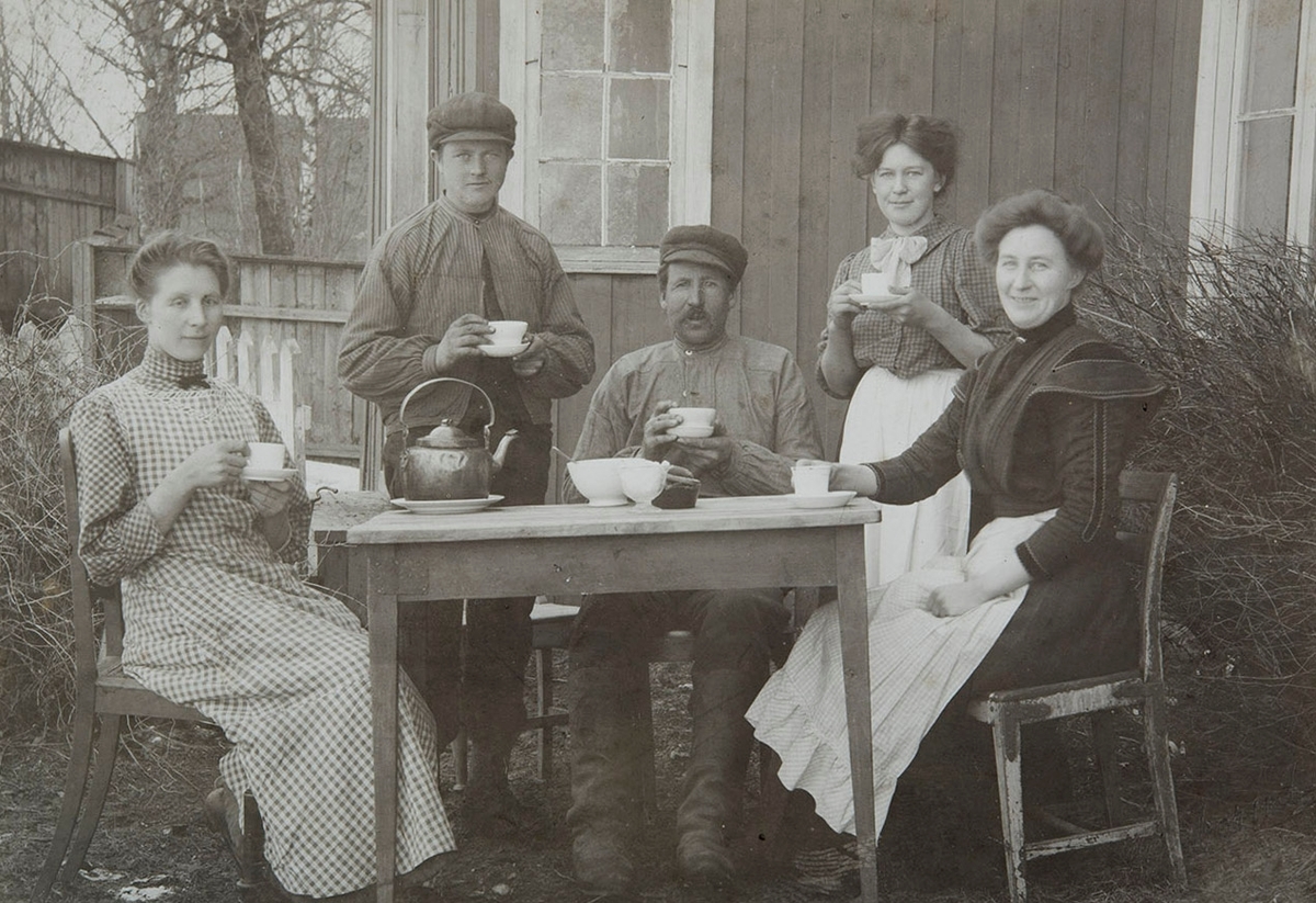 F.v Marie Amundsen, Sigurd Evensen, Vognmann Andreas Evensen, (til daglig kalt "Såstad") Ellen Jenny Evensen,  Gina Amundsen g. Evensen. fra Rekstadstranda. Familien Evensen bodde i 2 etg. på Ramseth-kafeen, Hamar. Bildet er muligens tatt i bakgården på Ramseth-kafeen. kaffebord, kopper,kjele,